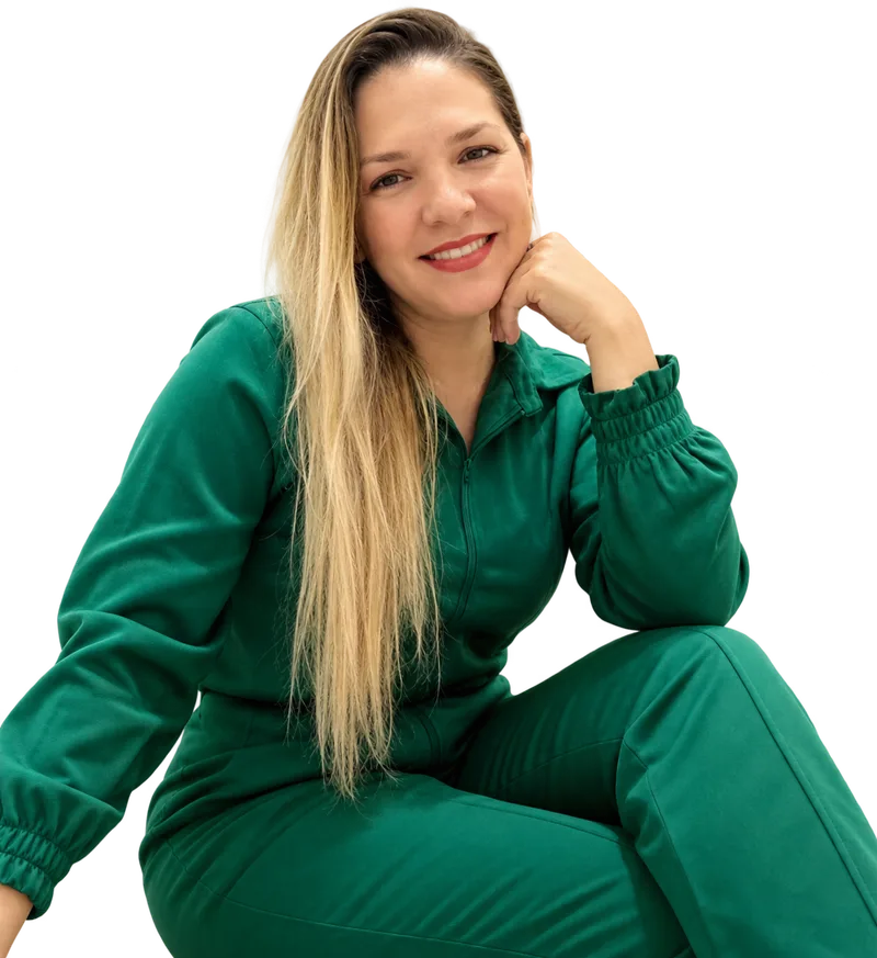 Maria Zuza, massoterapeuta, sentada e sorrindo, de uniforme verde